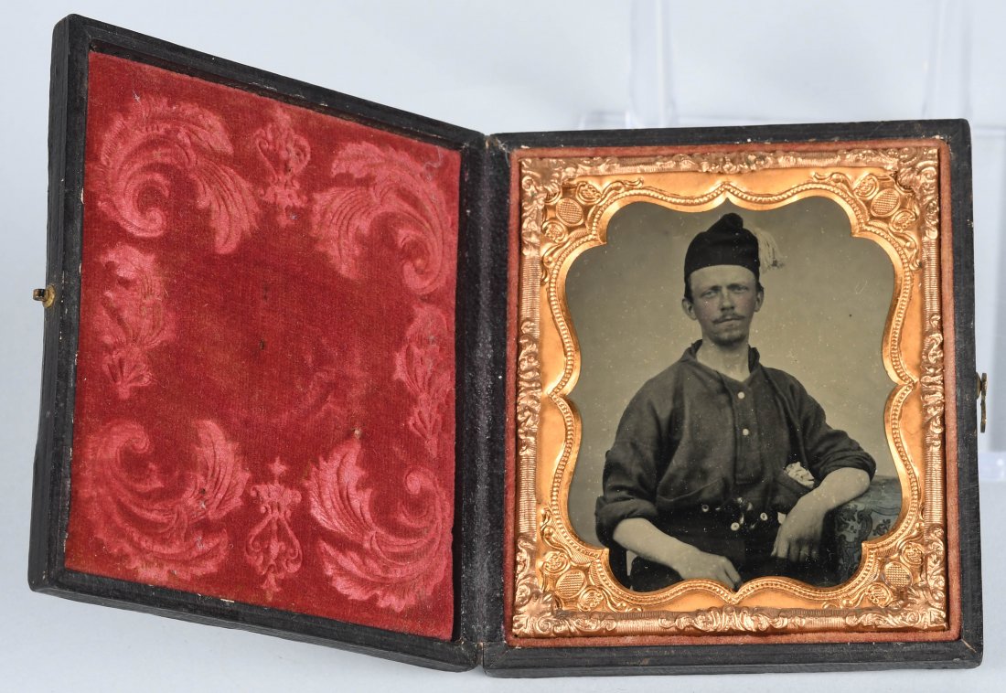 CIVIL WAR 1/6TH PLATE ARMED SOLDIER W SMOKING CAP: 1/6th plate ruby ambrotype of a Civil War soldier with a pistol tucked into his waist. He wears an unusual smoking cap with a tassel. Image is housed in a full case. excellent