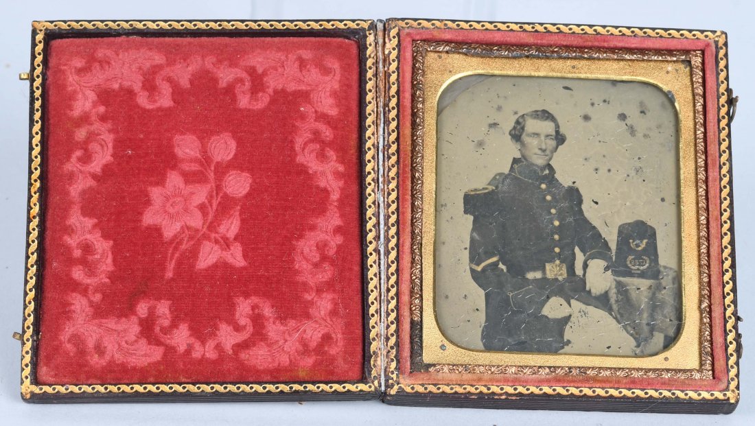 1850\'s 1/6TH PLATE AMBROTYPE SEATED SOLDIER: 1/6th plate ambrotype featuring a seated soldier with 8 button frock coat and eagle belt plate. Placed on the table next to him is a shako with pompom, infantry hunting horn and numbers/letters. Crazi