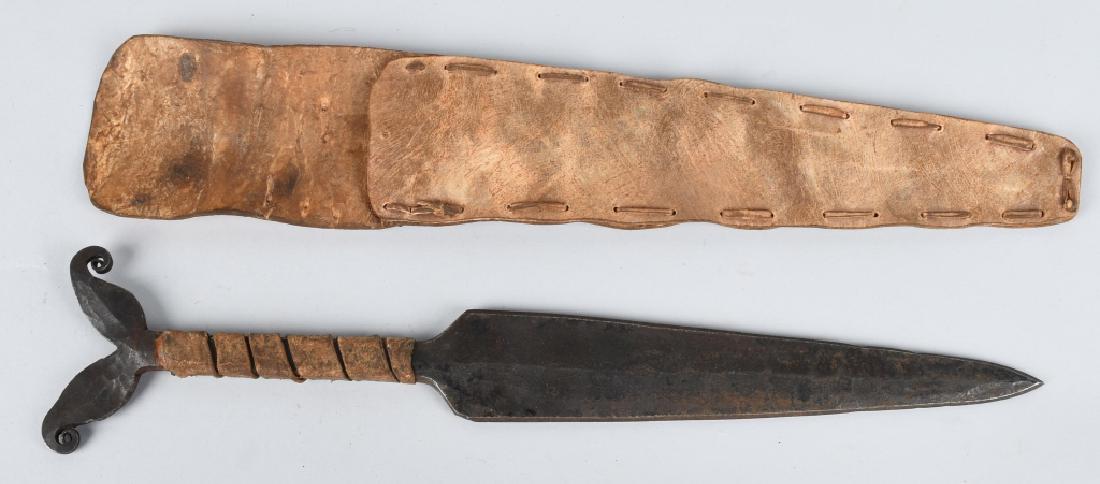 ATHABASCAN DOUBLE VOLUTE DAGGER & HIDE SHEATH: Hand forged spear dagger measuring 15 1/2" overall with a 9 1/2" blade. dating from the second half of the 19th century. The sheath and grip are made from raw hide. This is a Russian N.W. Coast trade 