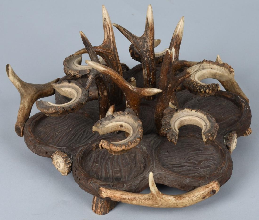 BLACK FOREST CARVED WOOD & ANTLER CRUET TRAY: Nicely made, antlers are carved to hold cruet bottles. Base is carved wood and footed with antlers. One antler has damage at end. 13" diameter. Very Good