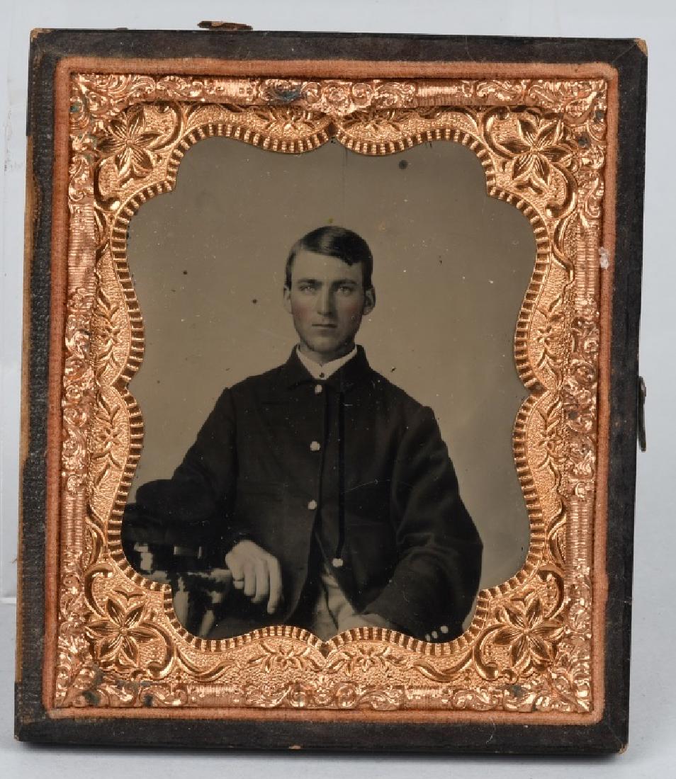 CIVIL WAR 1/6TH PLATE AMBROTYPE - UNION SOLDIER: 1/6th plate ruby ambrotype of a Union soldier wearing a 4 button sack coat and seated with his bummer's cap on a table next to him. Image is housed in a mat and 1/2 leatherette case. excellent.