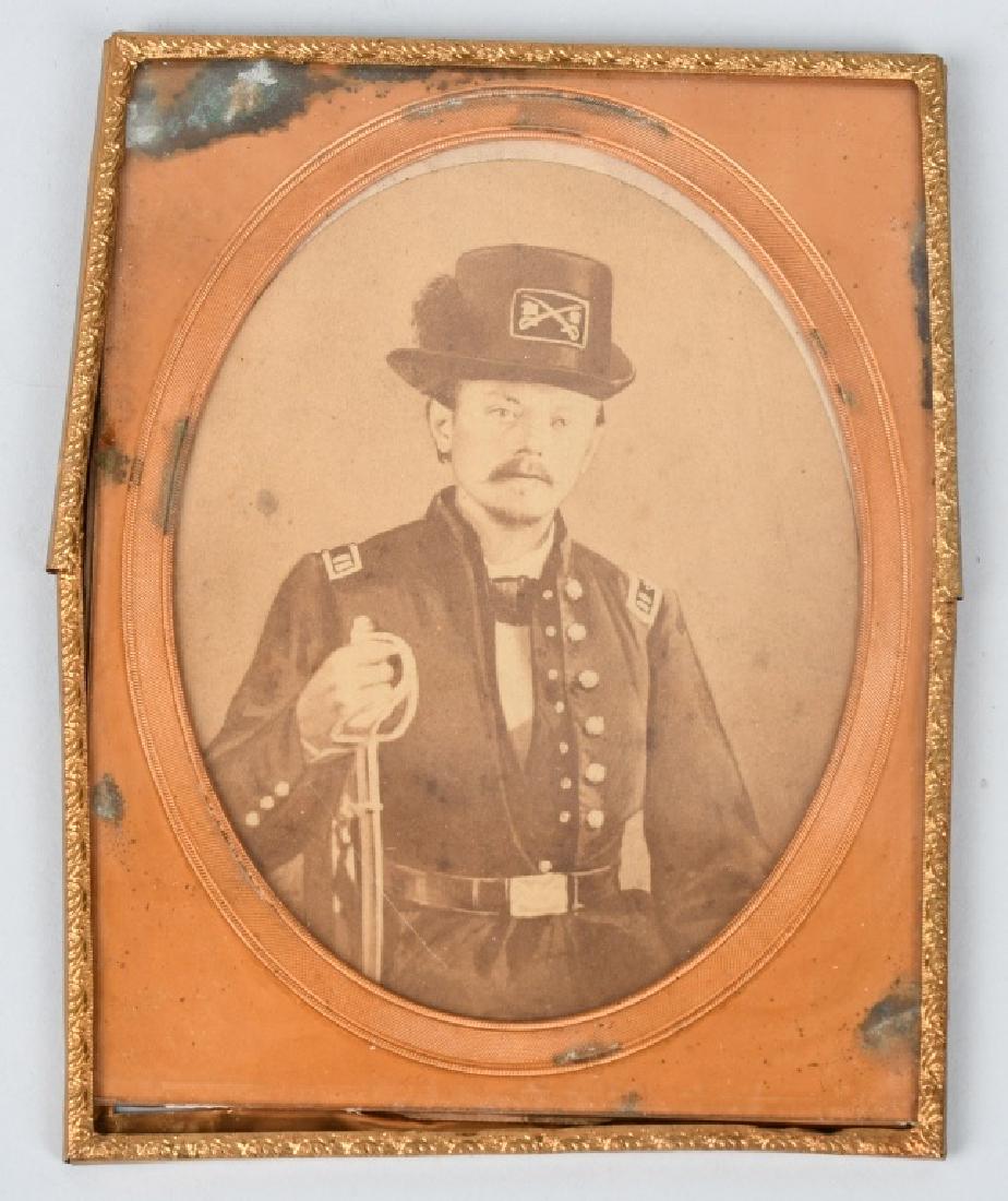 CIVIL WAR ALBUMEN UNION CAVALRY OFFICER 1/2 MAT: Albumen of an armed Union cavalry officer holding a cavalry saber. His Hardee hat is adorned with a very unusual rectangular shaped hat insignia. Image is housed in a 1/2 tintype mat and measures 5.5"
