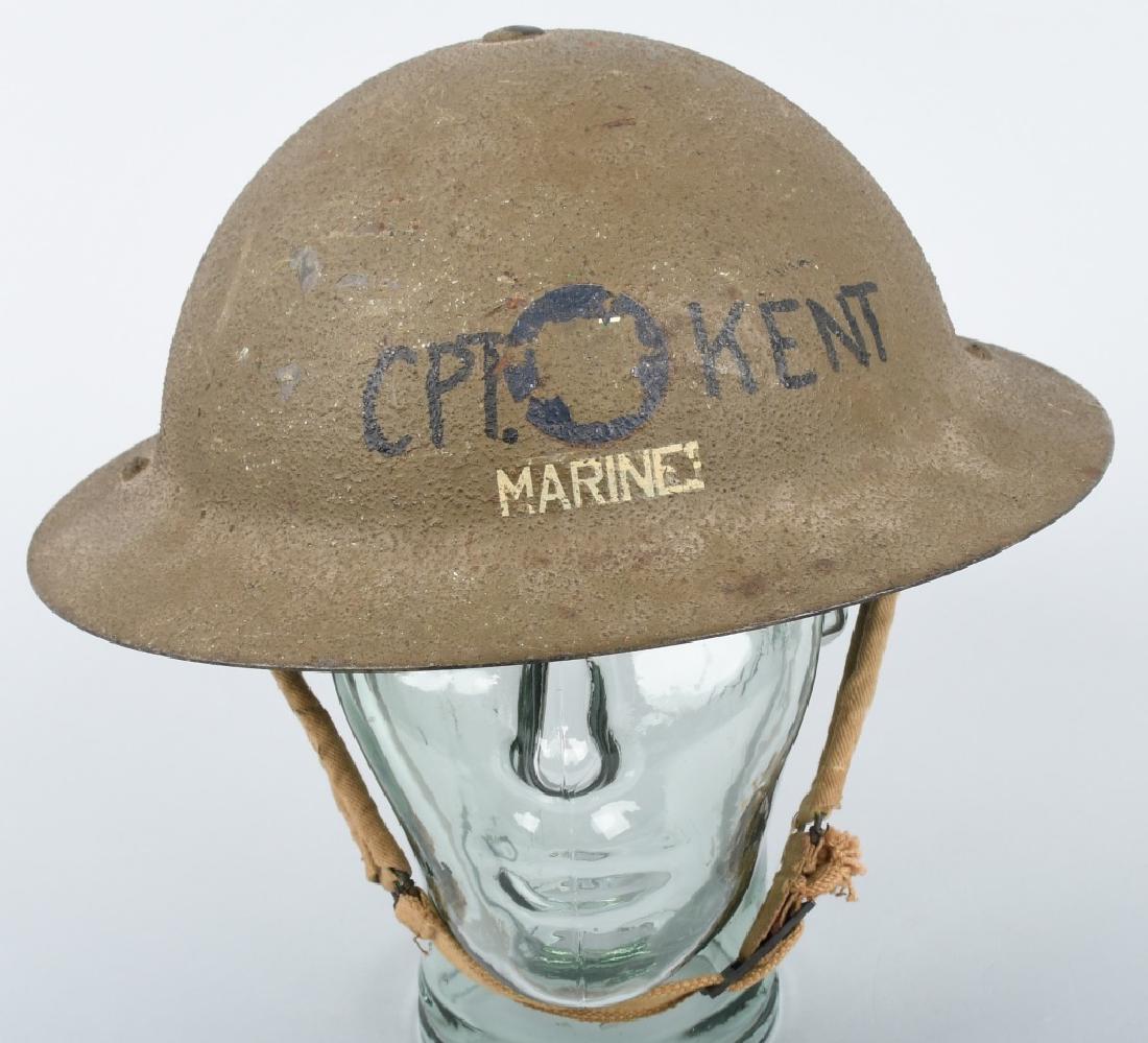 WWII BRITISH TOMMY / BRODIE HELMET, PAINTED MARINE: WWII British Brodie or Tommy helmet. Has khaki chinstraps and leather liner. Painted on the front is "CPT. KENT" and the word "MARINES" beneath it. OD Green paint over sawdust. Excellent.
