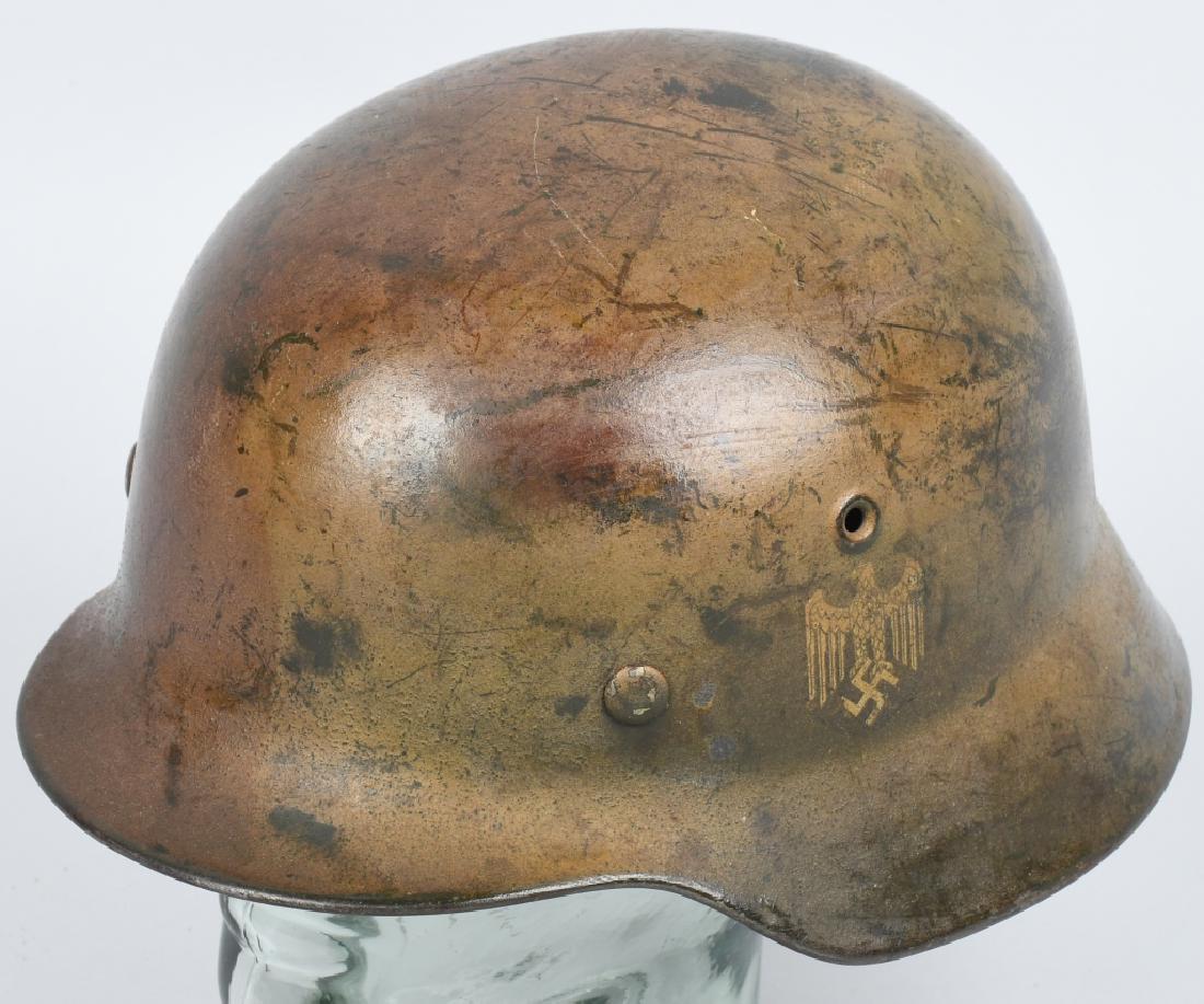 WWII NAZI GERMAN M40 CAMO SD ARMY HELMET W/ LINER: The stamped sheet steel construction helmet retains about 80% of its field-applied camouflage over-paint in random splotches of green tan and brown with spots of wear to the base steel. All three line
