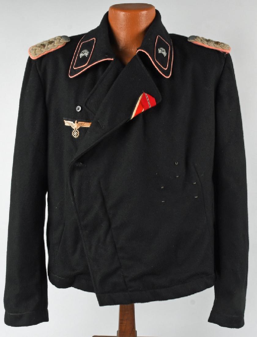 WWII NAZI GERMAN OFFICER PANZER WRAPPER: First pattern black wool/rayon blend construction waist length double breasted style tunic with fold back lapels and a large lay down collar. The left front closure panel of the tunic has four hidden 