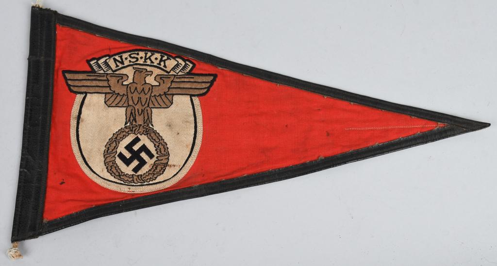 WWII NAZI GERMAN NSKK MEMBER'S VEHICLE PENNANT: A multi-piece cotton construction pennant 31cm across with a 17cm tall hoist edge. Sewn to both sides of its red field is a 85mm diameter white disk upon which is machine woven a copper-colored spread