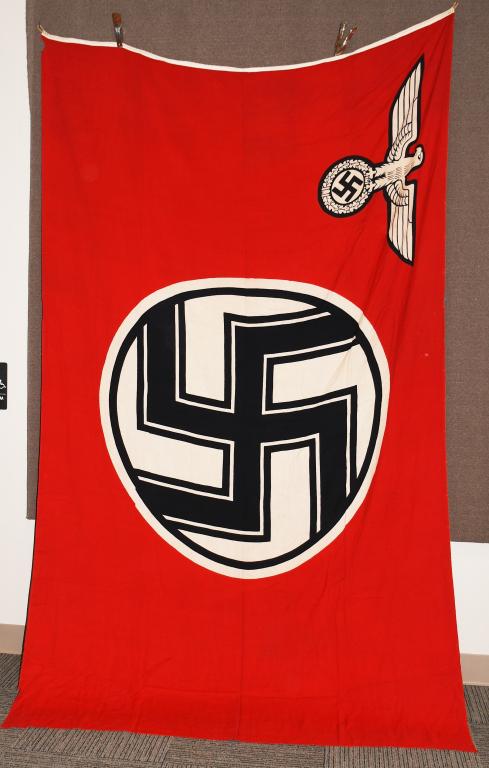 WWII NAZI GERMAN STATE SERVICE FLAG: A 1935 pattern double sided, printed cotton/linen construction flag. The flag features a red base field white with a white central, circular field with a black and white bordered black static swastika