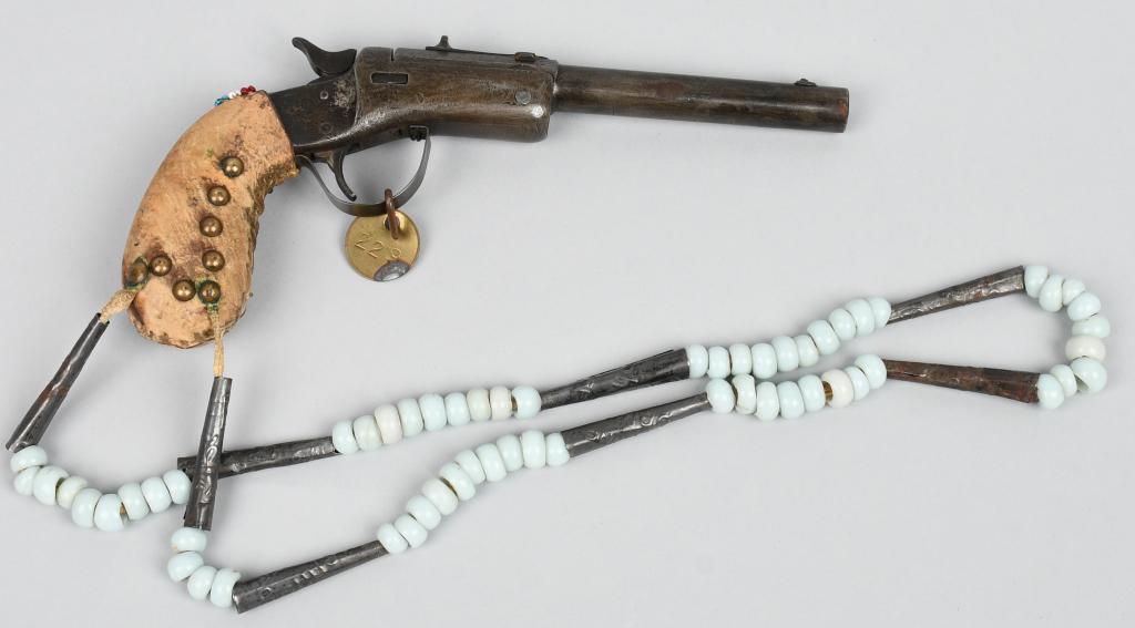 INDIAN DECORATED STEVENS SINGLE SHOT PISTOL: #34097. Gun has a 6" barrel, .22 caliber, no ejector, replace trigger guard and decorated with leather and brass brads over grips and attached beaded and silver lanyard. Not working nor is there any o