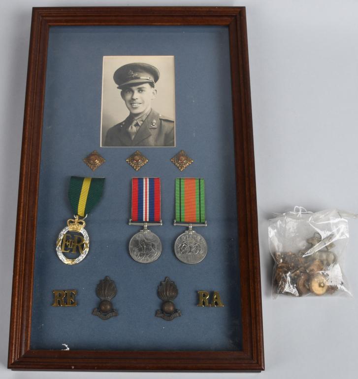 WWI BRITISH INSIGNIA & MEDALS GROUPING: Framed and matted trio of British medals - British Emergency Reserve Decoration, War Medal 39-45, and Defence Medal. Also includes "Ubique" Royal Artillery lapel badges, "RA" and "RE" pins for service