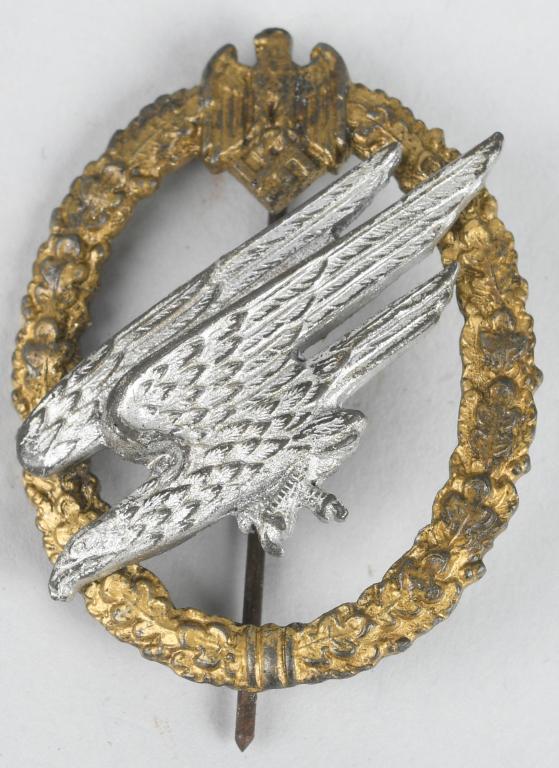 WWII NAZI GERMAN ARMY PARATROOPER'S BADGE: Two piece, die struck alloy construction badge with gilded and silver washed finishes. The badge is in the form of a vertically oval, oak-leaf wreath with a small Wehrmacht style eagle with down swept