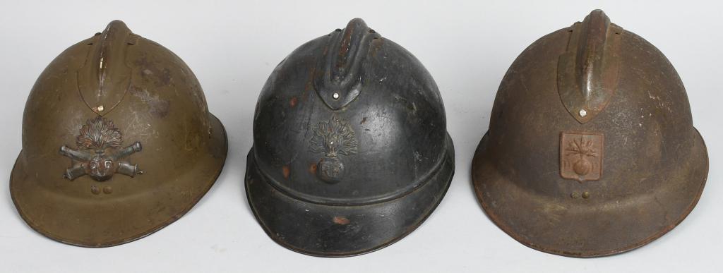 3 FRENCH ADRIAN STYLE M26 COMBAT HELMETS: Lot of 3 French combat helmets. Adrian Style, all three have insignia on the front. One is green with an Artillery front plate, missing a liner. One has an ordnance insignia and "D.P." on the front, a