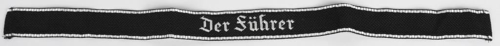 WWII NAZI GERMAN SS DER FÜHRER OFFICER'S CUFFTITLE: Early, (pre-December 1939) woven black rayon cufftitle with machine woven embroidered Gothic script "Der Führer" in bright silver/aluminum threads. The cufftitle is bordered at both top and bottom ed