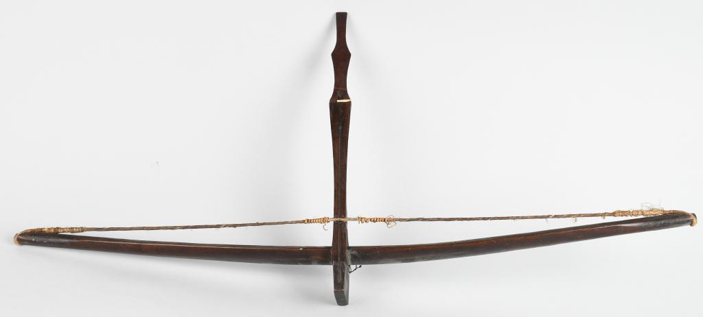 VIETNAM WAR MONTAGNARD CROSSBOW: Vietnam war era Montagnard crossbow with hide bow and wood construction. Slight crack on the underside near the front. Measures approximately 40" across and 20" long. Shows age and wear. Very Good