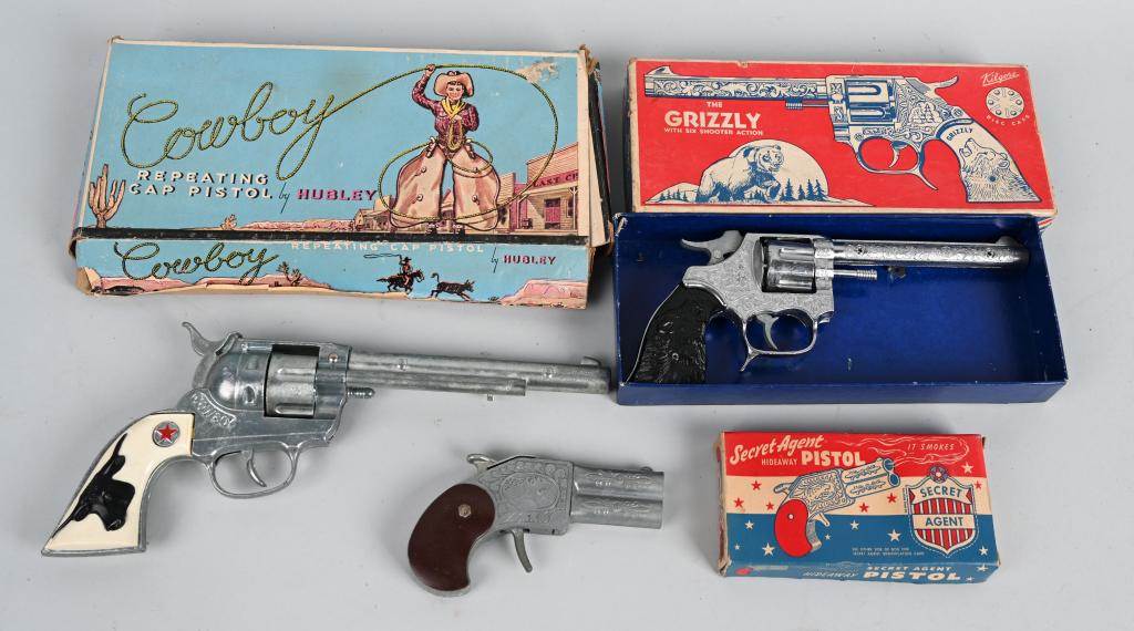 3- VINTAGE CAP PISTOLS w/ BOXES: Lot includes a Hubley Cowboy in working condition, a Hamilton Secret Agent that is working, along with a non working Kilgore Grizzly. Boxes show wear. Largest is 11 1/2". very Good-Excellent