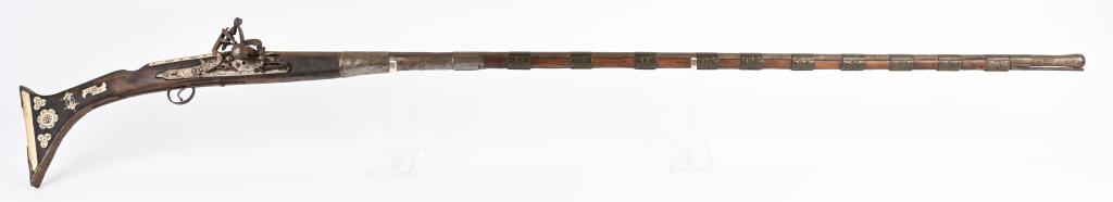 ORNATE MIDDLE EASTERN LONG BARREL FLINTLOCK RIFLE: Barrel measures 55" with 11 decorated brass barrel bands. Stock has 20 scrimshaw decorated bone inserts. Intricate flintlock system. All metal has nicely toned and not cleaned. Full length stock is ni