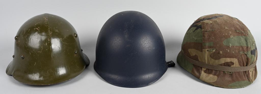 3 WORLD HELMETS US BULGARIA SWITZERLAND: Lot of 3 military helmets. US M1 Steel Pot style helmet with liner and an incorrect but fitted PASGT woodland camouflage cover, a Swiss blue M1 clone helmet which appears to be unissued, and a Bulgari