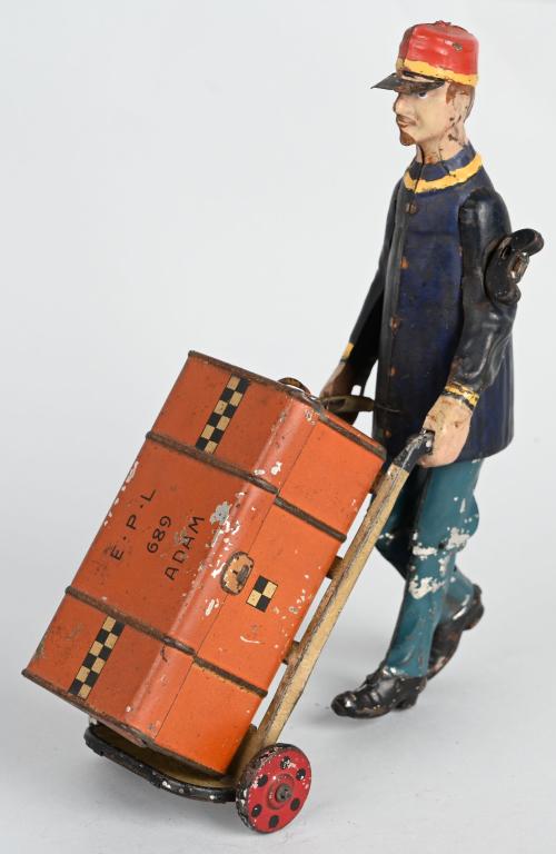 LEHMANN TIN WINDUP ADAM THE PORTER w/ TRUNK: Nice original Adam the Porter. Unusual version with blue pants. Windup works good. Comes with original truck that is missing 1 side panel. 8' Very Good-Excellent