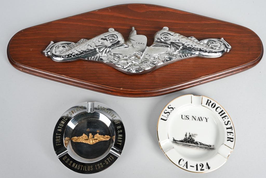 3 US NAVY PIECES SUMBARINE USS NAUTILUS + ROCHESTR: Includes a wooden plaque with silver "dolphins" US Navy submariner's badge, a metal ashtray which has a gold submariner's badge in the center and the words "First Atomic Powered Submarine of U.S. Navy