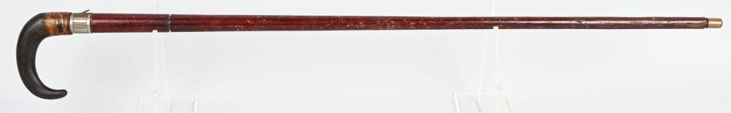 UNMARKED ANTIQUE CANE GUN: Cane opens up to a 2 1/2" chamber for a cartridge shell approximately .410 with fold down trigger, bone handle with old tape repair, brown faux wood painted steel shaft with brass cap. Homogenous wear