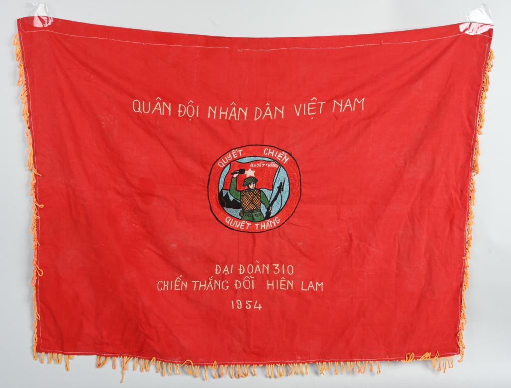 1954 VIETNAM DATED BATTLE FLAG OF INDEPENDENCE: 1954 dated North Vietnamese battle flag for the 310th Regiment. Flag measures 30 X 42 including gold fringe. Center of the flag has a well armed soldier holding a grenade and rifle with the inscriptio