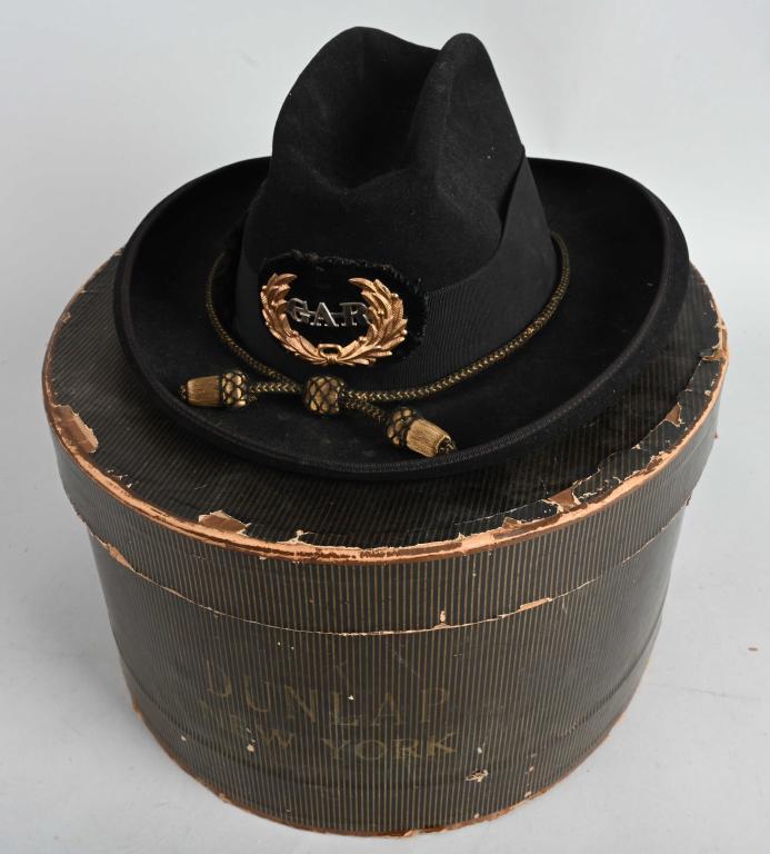 GAR FELT SLOUCH HAT WITH CORDS IN BOX: Felt hat with rolled brim, hat band, and hemmed brim. Has wreathed "G.A.R." Grand Army of the Republic badge in the center which is mounted to a black velvet pad and hand sewn to the hat. Also has bla