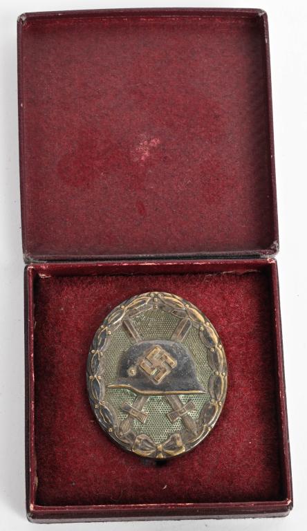 WWII NAZI GERMAN CASED GOLD WOUND BADGE WW2: 1939 pattern, die struck, alloy construction, solid backed badge with a gilt wash mostly missing. The badge is in the form of an embossed, vertically oval, laurel leaf wreath encompassing an embossed