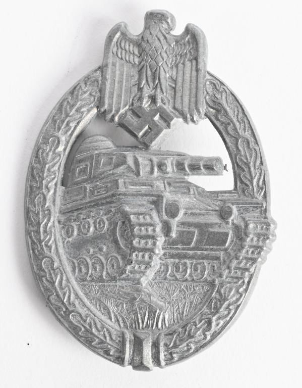 WWII NAZI GERMAN PANZER BADGE IN SILVER WW2: German World War II Army Silver Tank Assault Badge. The front shows a tank in the center with a German eagle clutching a swastika in his talons at the top. Both are surrounded by an oval oak leaf wrea