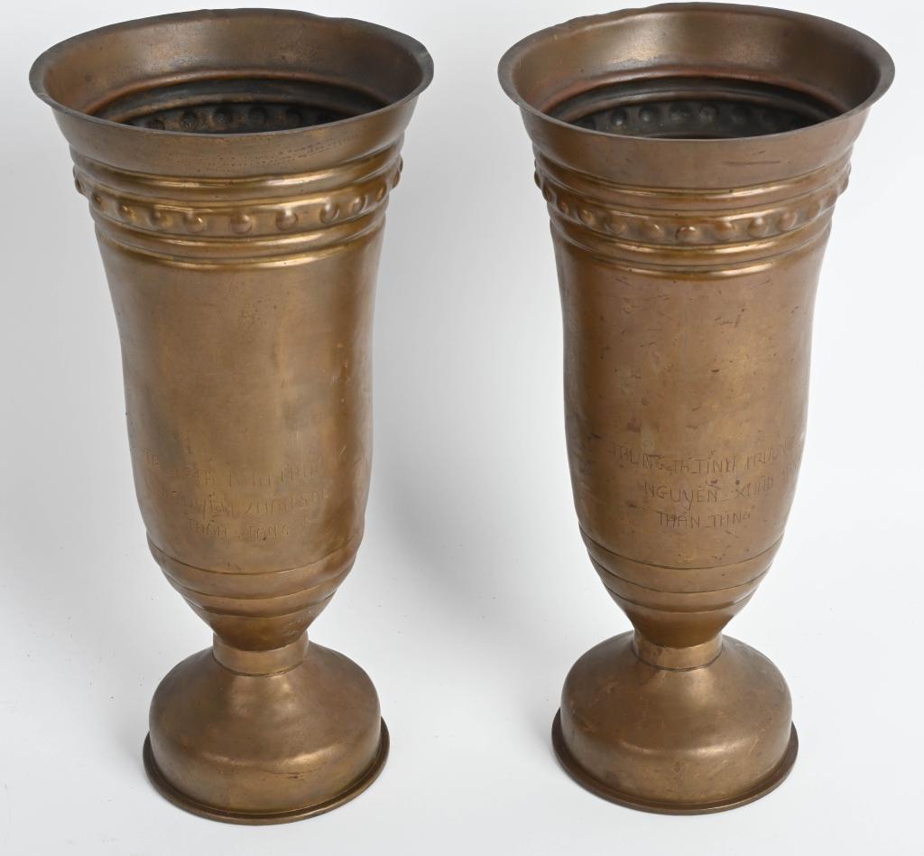 2 VIETNAMESE ENGRAVED 1969 DATED 105MM VASES: Pair of 1969 dated 105mm Artillery shells with a hand engraved inscription. The words in Vietnamese "trung ta tinh truong nguyen xuan sanh than tang" appear near the base of both pieces. Trench art va