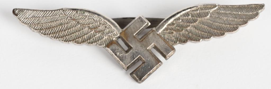WWII NAZI LUFTWAFFE CIVILIAN RADIO OPERATOR BADGE: (Luftwaffe Ziviles Flugzeugfüherabzeichen mit Etui). Constructed of silvered tombak; the obverse consisting of a winged mobile swastika; the reverse plain, with a horizontal slender banjo style pinba
