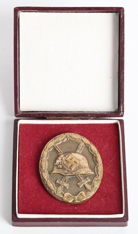 WWII NAZI GERMAN CASED GOLD WOUND BADGE WW2: 1939 pattern, die struck, alloy construction, solid backed badge with a gilt wash. The badge is in the form of an embossed, vertically oval, laurel leaf wreath encompassing an embossed profile of a M3