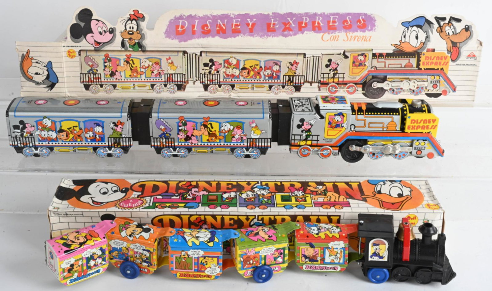 2- ARGENTINA WALT DISNEY TRAINS w/ BOXES: Includes Doll Toys Disney Express Con Sirena tin friction Train. Plus Doll Toys Disney Train A Cuerda tin windup Train. Both with great colors and graphics. Both like new in boxes. Largest 23" Excelle