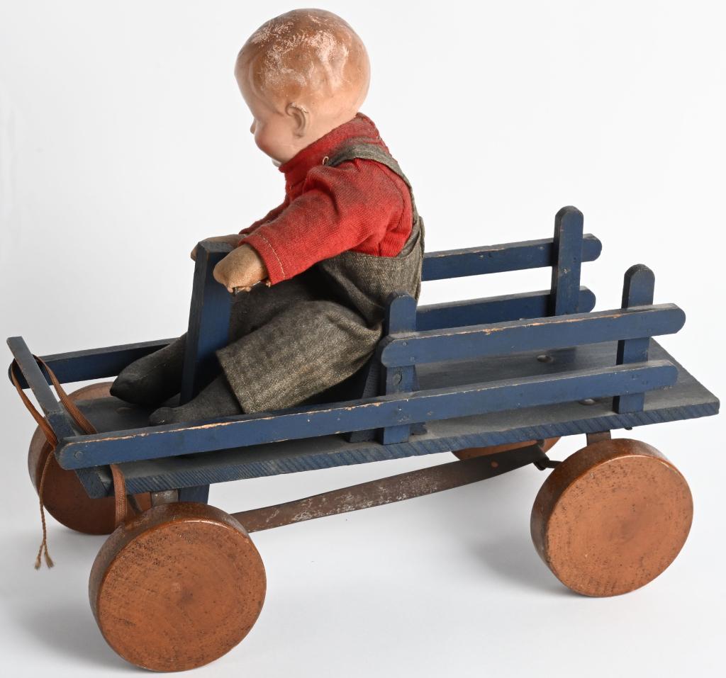 EARLY DOLL ON IRISH MAIL TOY: The stake bed Irish Mail is mechanical when pushed. The boy rocks back and forth. The doll has compisition head, cloth body and is dressed. Has general wear and cracks in composition. 13", Very Good