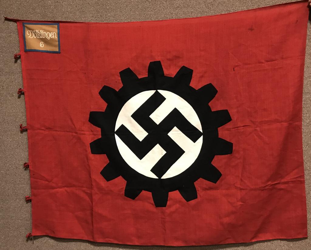 WWII NAZI GERMAN DAF FLAG ORTS LEVEL Völklingen: A 1937 pattern, 125cm x 120cm, double-sided multi-piece cotton construction factory unit flag. The flag features a red base field upon which is sewn a white bordered, black DAF fourteen cog wheel enco