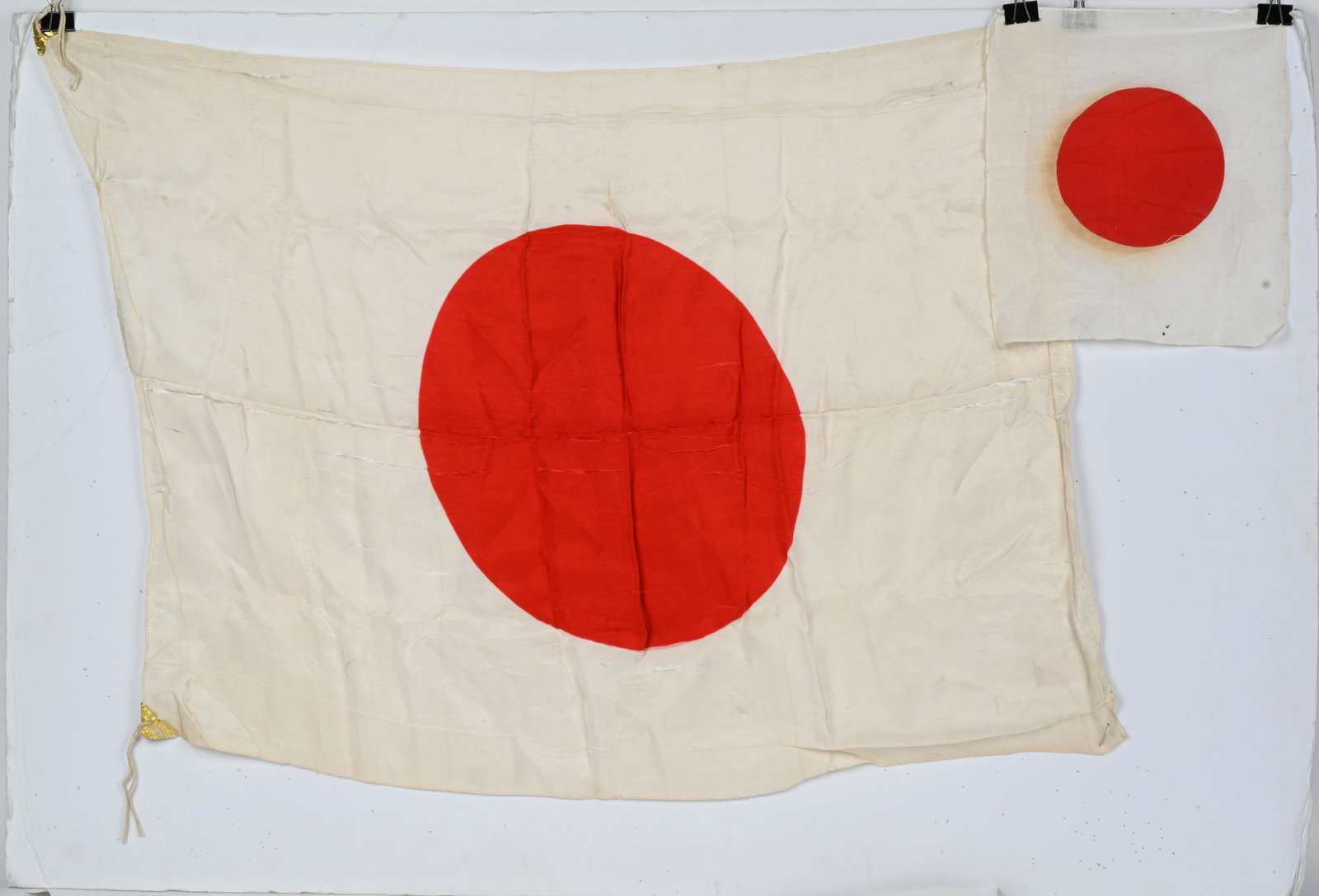WWII JAPANESE BAYONET FLAG AND MEATBALL WITH TAG: 10.5 x 13.5 cotton small sized WWII Japanese bayonet flag, 40" x 30 silk flag with original gold foil corners AND remarkable paper Japanese tag. Large meatball has light separation. Very Good
