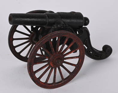 ANTIQUE CAST IRON TOY CANNON: The cannon has a 5 1/2" barrel and is 7 1/2" overall. Original black paint with 4" red military style wheels. No breaks or repairs. Very Good