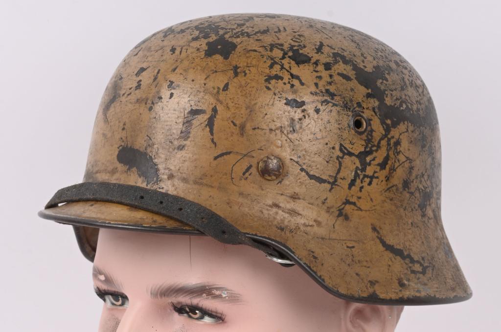 WWII NAZI GERMAN M40 COMBAT HELMET TAN CAMOUFLAGE: The stamped, sheet steel construction helmet retains a good portion of its original tan overpaint. All three liner retaining rivets are intact. The interior of the helmet has an M31 tan leather liner 