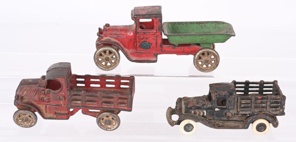 3- CAST IRON TOY TRUCKS: Lot includes an Arcade Dump Truck, a A.C. Williams Mack Stake Truck and a A.C. Williams take-a-part Stake Truck. No cracks or breaks. A.C. Williams take-a-part is over painted and has replaced tires. 