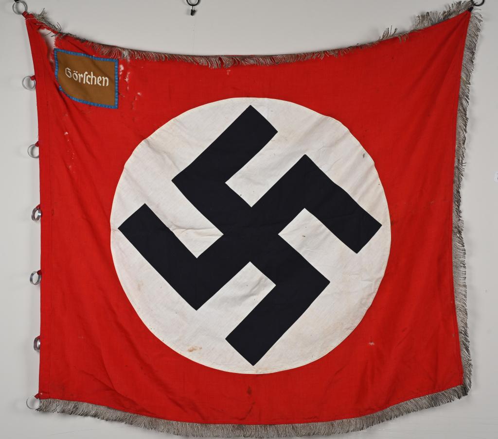 WWII NAZI GERMAN NSDAP ORTS LEVEL FLAG GORSCHEN: WWII Nazi German flag is for the town of Görschen which is in Saxony. This Orts level flag measures 46 inches X 54 inches showing several holes into the body of the flag. The double-sided, multi-piec