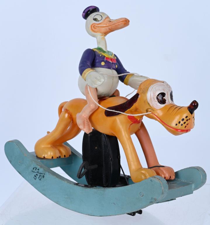 JAPAN CELLULOID WINDUP DONALD & PLUTO ROCKER: Large and impressive celluloid windup Donald Duck riding Pluto Rocker. Toy has some repairs. Displays great and windup works. 8" Excellent
