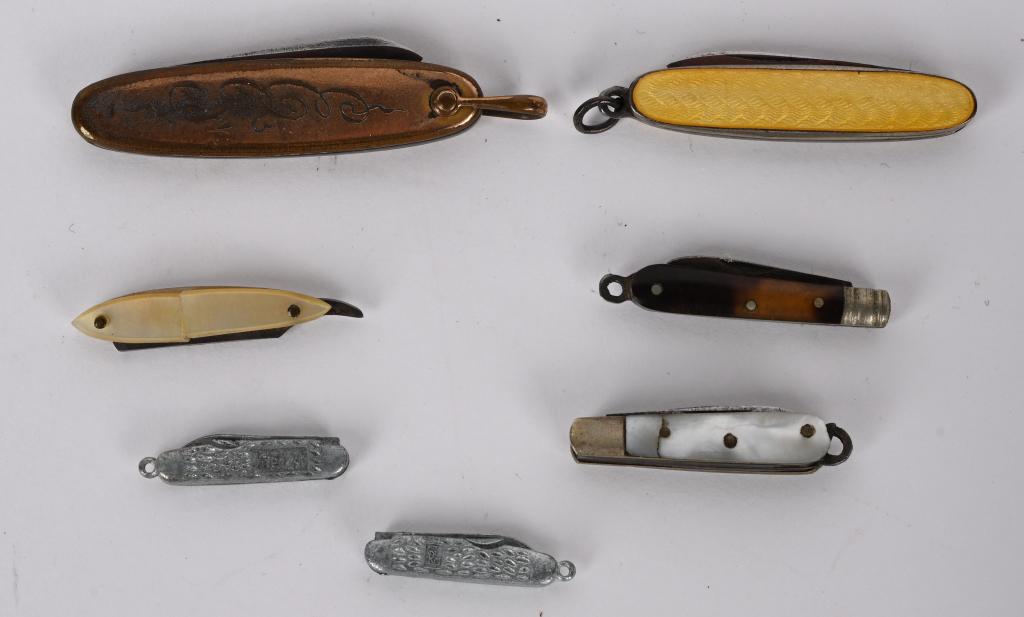 COLLECTION OF 7 MINIATURE FOLDING KNIVES: Unique assorted collection of 7 Miniature collectors knives. 2 with mother of pearl 1 with celluloid scales 1 bronze finished and one with bakalite scales. 2 are cast with folding single blade. A uniq