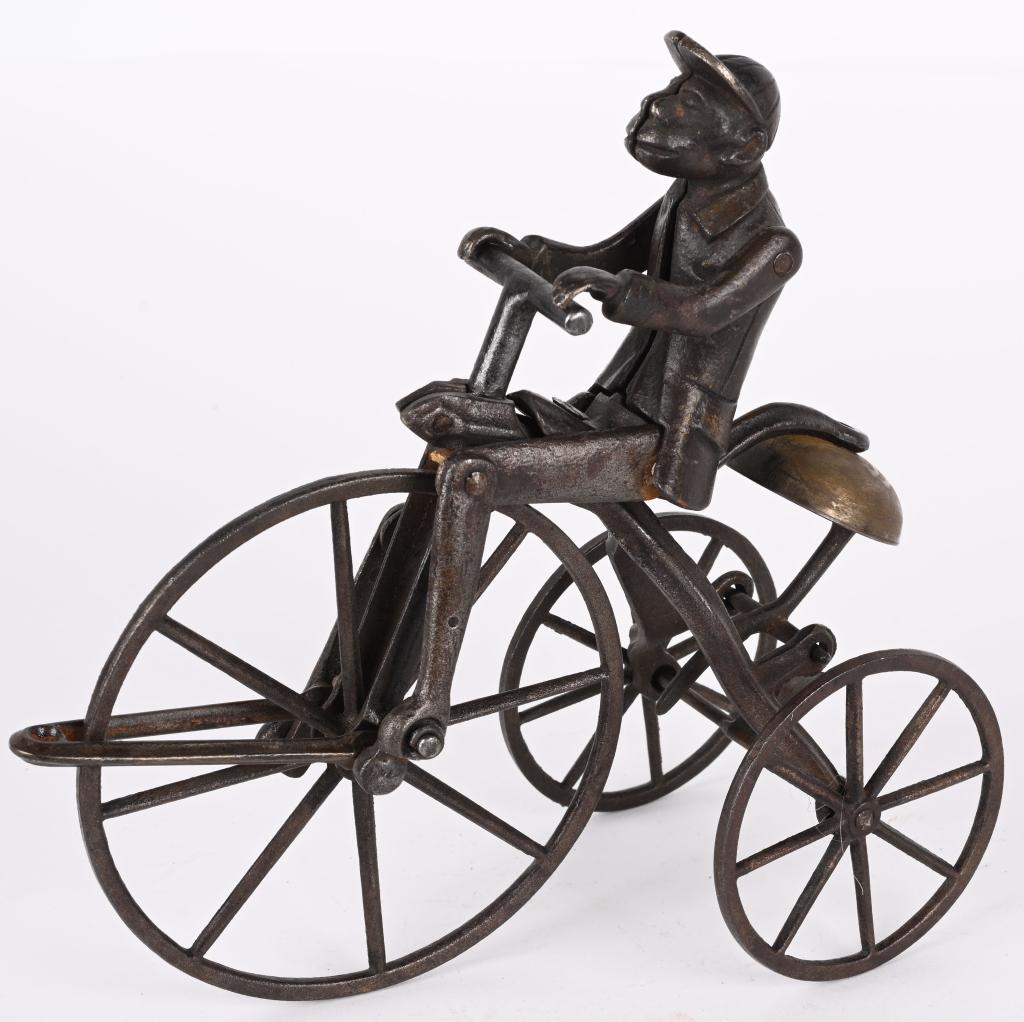 STEVENS CAST IRON MONKEY ON TRICYCLE BELL TOY: J. & E. Stevens Monkey Tricycle Bell Toy cast iron with japanned finish. Monkey wears jacket and cap with articulated legs, riding a tricycle. No cracks or breaks, and finish has wear. Displays great.