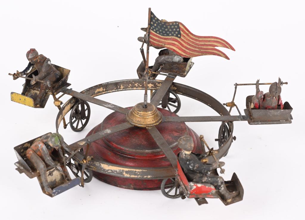 GERMAN HAND-PAINTED WINDUP CARNIVAL RIDE GO-ROUND: German Hand-Painted Tin Carnival Ride Go-Round. All complete with Riders in each Seat. Has windup that works. Some solder joint repaired or loose. Flag replaced. 10" Very Good