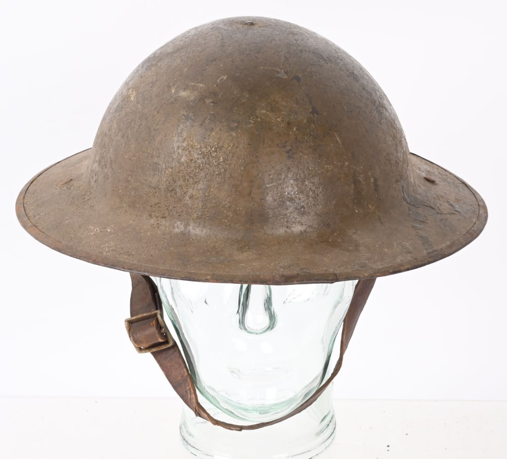 WWI BRITISH WWI MK1 COMBAT HELMET WITH LINER WW1: A second pattern (with a magnetic steel rim instead of a raw edge) Mark l non-magnetic hardened manganese steel helmet. Nice complete liner and chinstrap system. To the underside of the rear brim of t