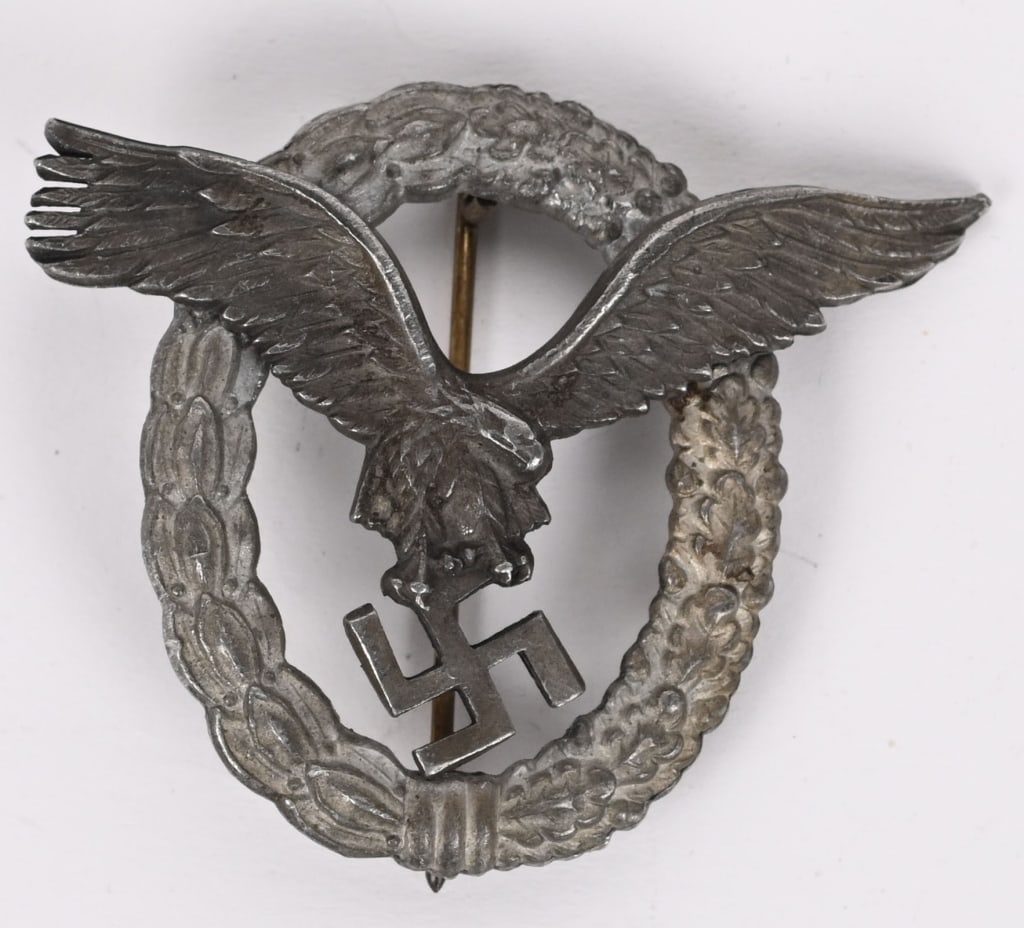 WWII NAZI GERMAN LUFTWAFFE PILOT BADGE WW2: Late war zinc alloy construction, two piece badge is in the form of a vertically oval wreath with a separate burnished silver finished, stylized, spread winged eagle in flight, clutching a swastika mo