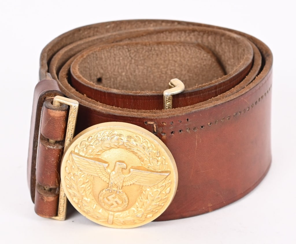 WWII NAZI NSDAP POLITICAL LEADER'S BELT & BUCKLE: A 57mm wide, 90cm long, Havana brown leather belt, with its cast, gilt-washed aluminum belt buckle. The roughly 56mm diameter buckle features, to its convex obverse, a spread-winged eagle clutching a 