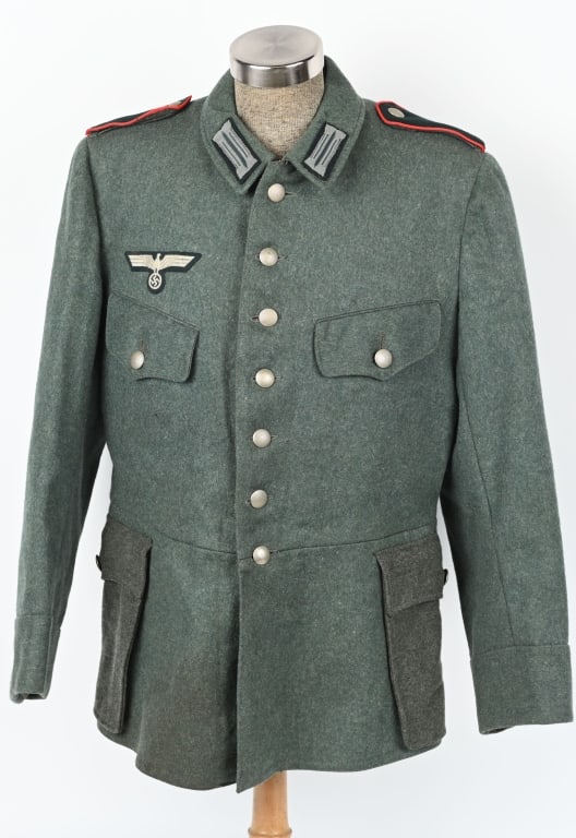 WWII NAZI RUSSIAN POA FIELD BLOUSE WITH SHIELD WW2: Field-gray wool/rayon blend construction field blouse features a vertical, seven button front closure with a single metal hook and eye positioned at the neckline. The field blouse has four front pocke