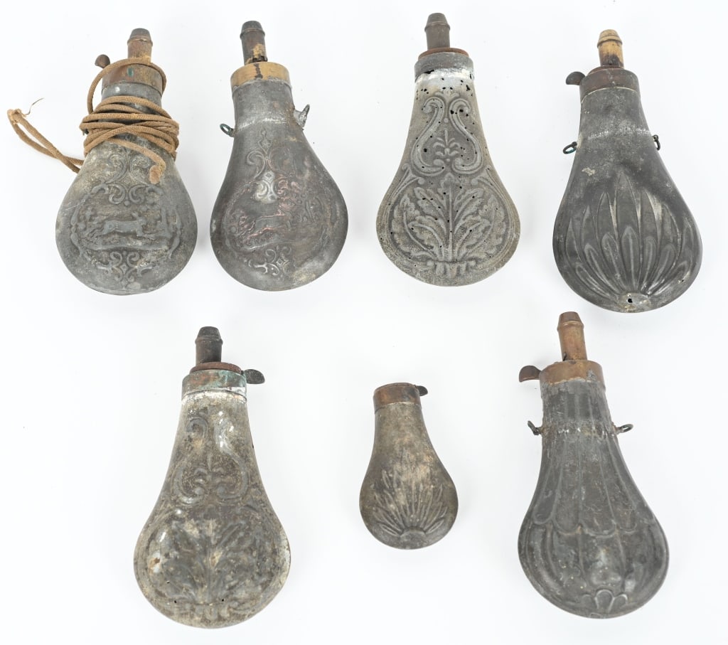 7- ANTIQUE ZINC POWDER FLASKS: Lot includes: 1. 6 1/2 embossed rabbit no spring, re soldered top. 2. 6 1/2" embossed rabbit. 3. 6 1/2" floral design with corrosion and mothing. 4. 6 1/2" floral design with corrosion and mothing 5.