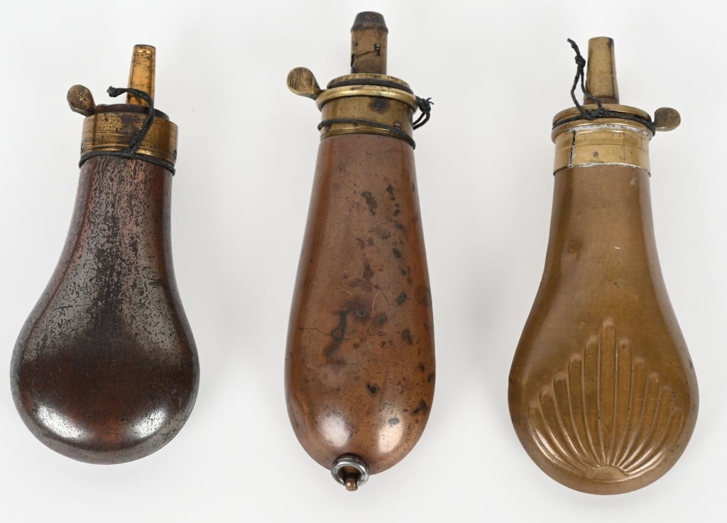 3- BRASS & COPPER PISTOL POWDER FLASKS: Lot includes: 1. 5 1/4" James Dixon Sheffield bag flask, missing spring, 2. 4 3/4" unmarked flask with original lacquer, likely Colt. complete, 3. 5 1/4" unmarked shell design flask, with patent top, 