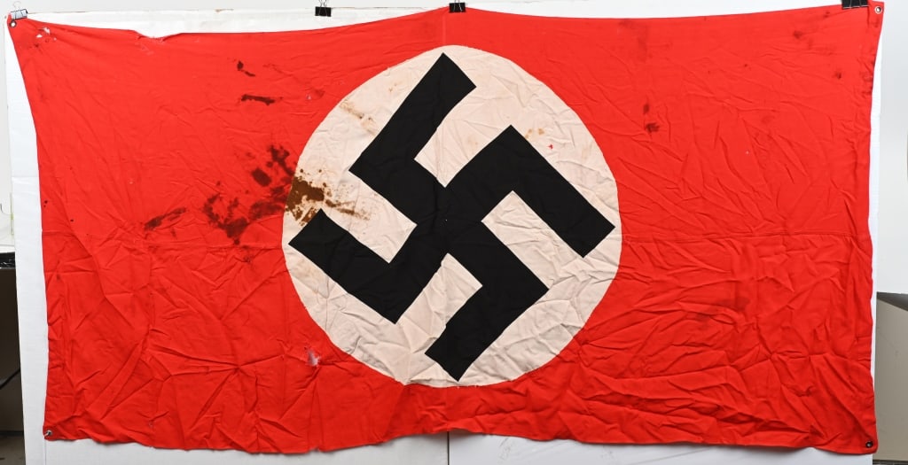 WWII NAZI GERMANY VEHICLE ID SINGLE SIDED FLAG WW2: Multi-piece single sided cotton construction banner approximately 74X40 and features metal grommets to each corner. To both its red fields are sewn white disks with printed mobile swastikas in black.