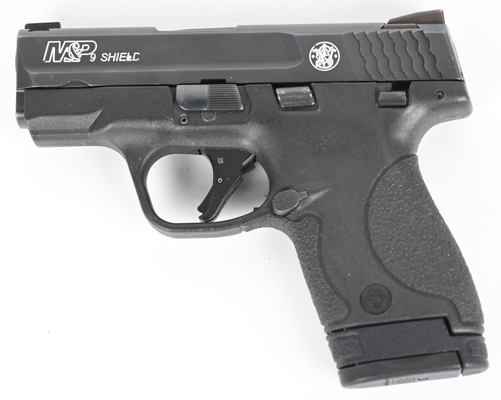 SMITH & WESSON MODEL M&P 9 SHIELD: SERIAL NUMBER: HVX1705. BARREL: 3-1/4". CALIBER: 9MM LUGER. MANUFACTURED: 2010S. Trijicon H3 sights. Blued slide and black polymer frame. Includes factory 8 round metal magazine. CONDITION: Very good